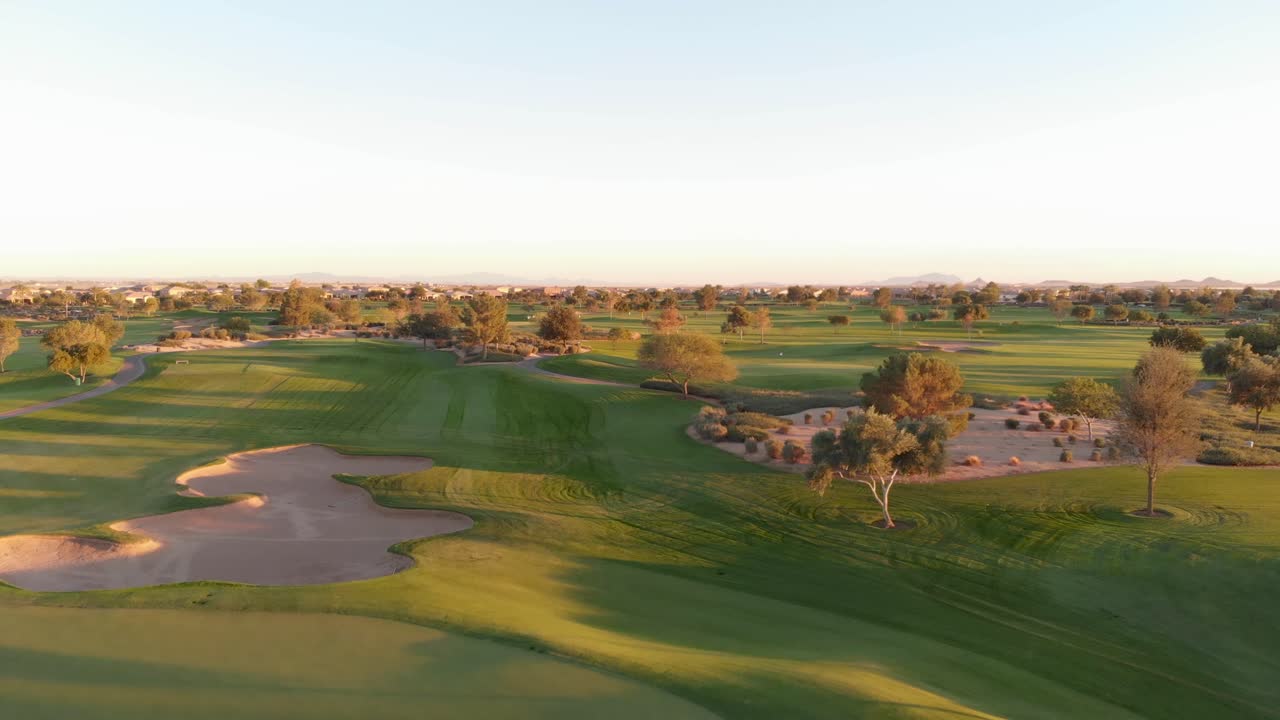Drone footage from a golf course near a residential neighborhood in Arizona. Low to high shot from the water hazard to reveal the greens