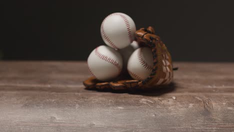 Cerrar-Estudio-De-Béisbol-Bodegón-Con-Pelotas-En-El-Guante-Del-Receptor-En-El-Suelo-De-Madera