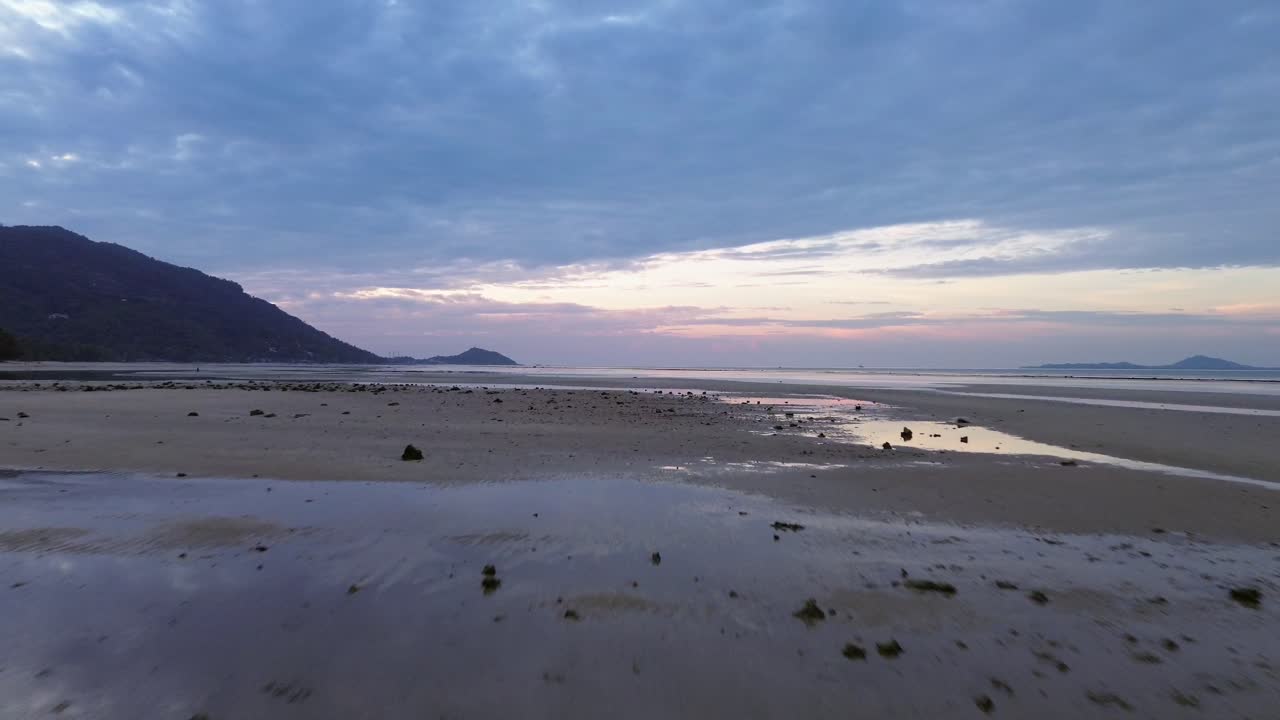 Beautiful aerial drone footage of sunrise over Koh Phangan, Thailand, featuring a pink horizon, calm sea, tropical coastline, and scenic island landscape in morning light