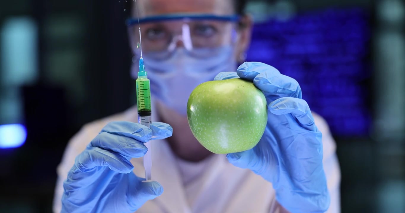 Scienziata espelle aria da una siringa vicino a una mela in laboratorio.