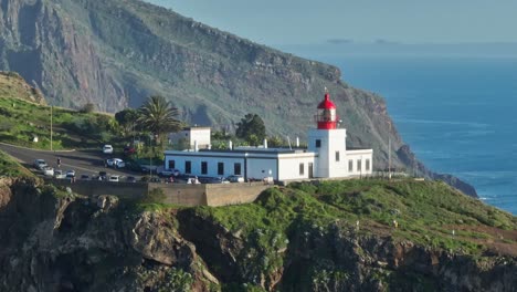 telephoto aerial parallax around white and red lighthouse in madeira portugal with epic cliffs behind