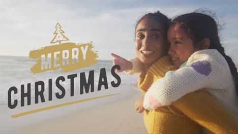 Animation-of-merry-christmas-text-over-biracial-mother-and-daughter-at-beach