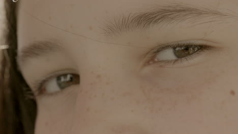 extreme closeup on pretty brown eyes of teen girl as she turns and looks into camera