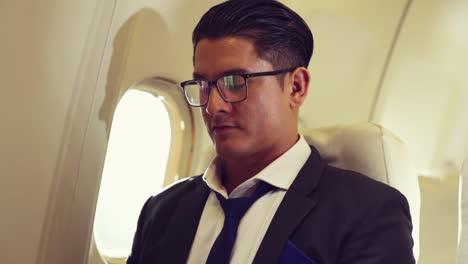 young businessman using laptop computer in airplane