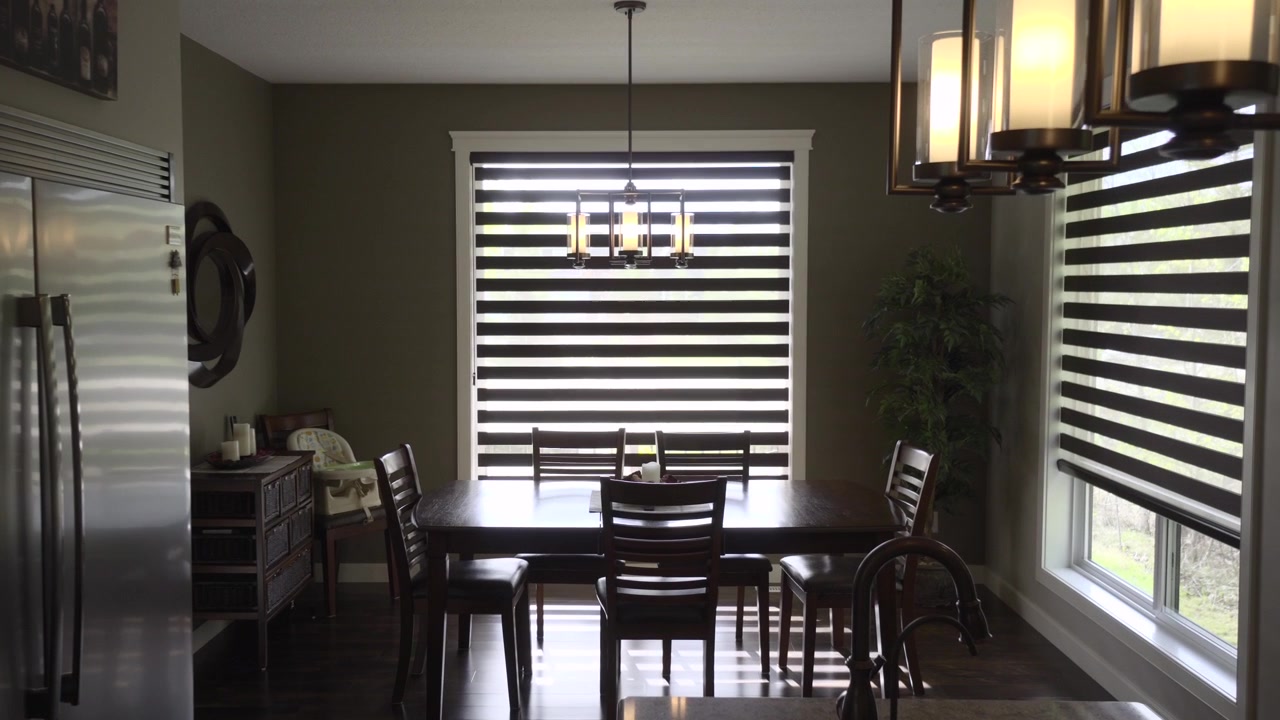 A dining room with lovely lights in the foreground, as well as a beautiful chandelier over the table
