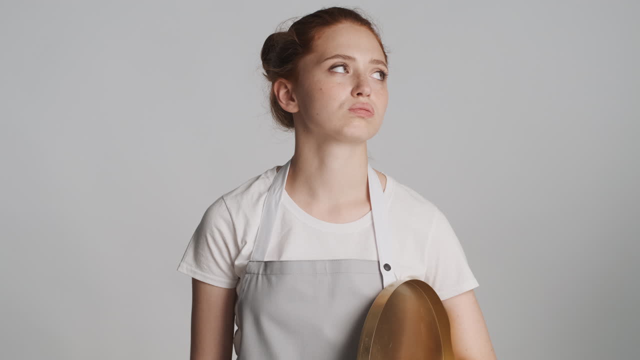 Redheaded waitress in front of camera on gray background.