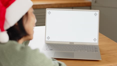 senior wearing santa hat video chatting on laptop at home during christmas, copy space