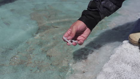 Hombre-Extrayendo-Cristales-De-Sal-Del-Estanque-De-Agua-Salada-En-Salinas-Grandes-Salar