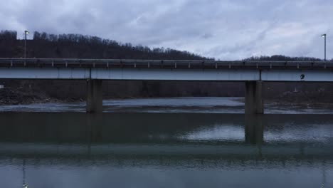 drone shot flying over a river and under a bridge