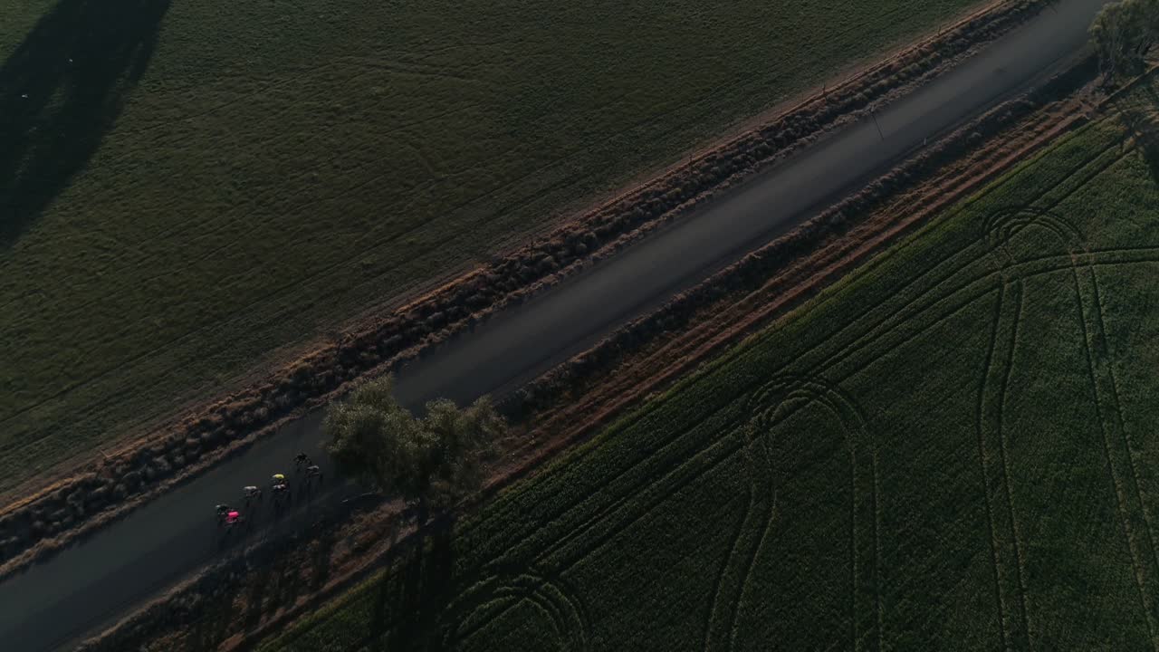 Aerial view of a small group of cyclist riding along country roads with lush green crop fields in the rural city of Wagga Wagga NSW Australia.