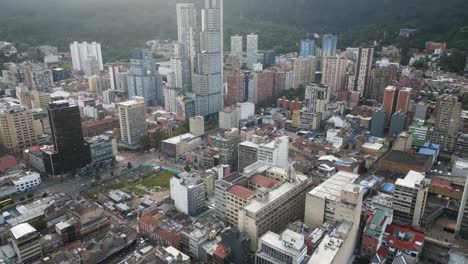 un avión no tripulado revela un moderno rascacielos en el corazón de bogotá, la capital de colombia, con el paisaje de las montañas de los andes en el fondo.