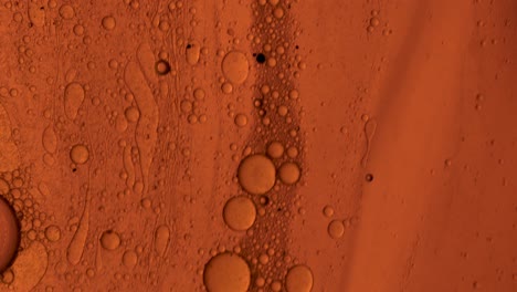 orange oily gel that flows over a stain-like surface with bubbles of oil