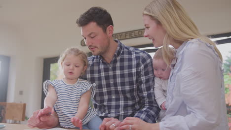 familia en la cocina con la hija dibujando en un libro y la madre sosteniendo al bebé hijo - filmado en cámara lenta