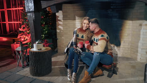 loving couple warming in the evening near fireplace. same knitted sweaters on male and female.