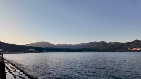 calm sea reflecting the golden hour light with a mountain range in the background in nachi bay, japan
