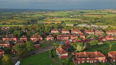 Zona-Residencial-De-Yorkshire:-Vista-Aérea-Por-Drones-De-Viviendas-Municipales-De-Ladrillo-Rojo,-Disfrutando-De-La-Luz-Del-Sol-De-La-Mañana-Y-Animada-Por-La-Actividad-De-Los-Residentes.