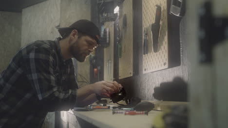 Person-wearing-hat-repairing-tools-at-garage,-side-view