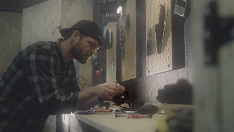 Person wearing hat repairing tools at garage, side view