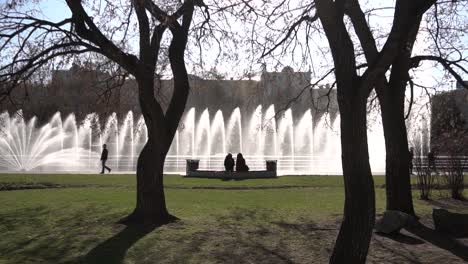 people relaxing by fountains in a city park