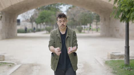 young man performing a magic trick in a park