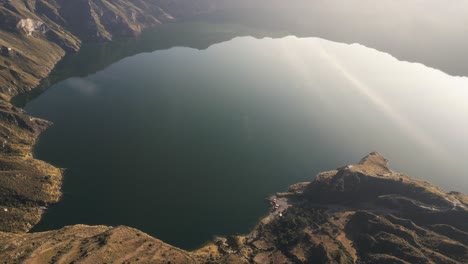 Quilotoa-Lake-at-Quilotoa-crater-in-Ecuador,-high-drone-view-with-sun-reflecting-in-water