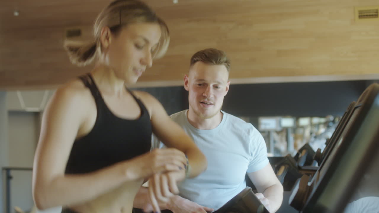 Woman Training on Treadmill with Gym Instructor