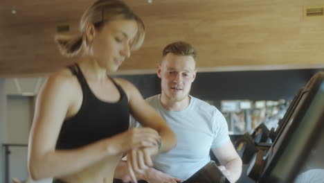woman training on treadmill with gym instructor