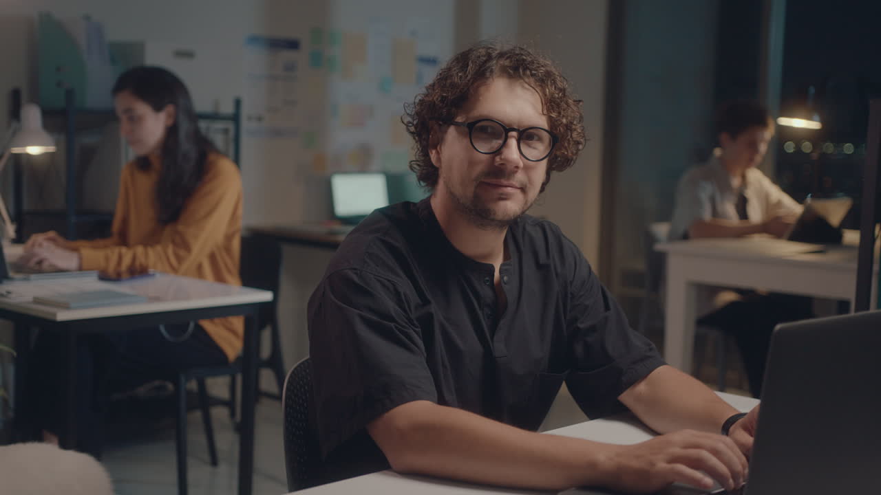 Young Man Posing on Camera at Office Workplace during Night