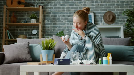 woman taking medication while resting on a couch at home