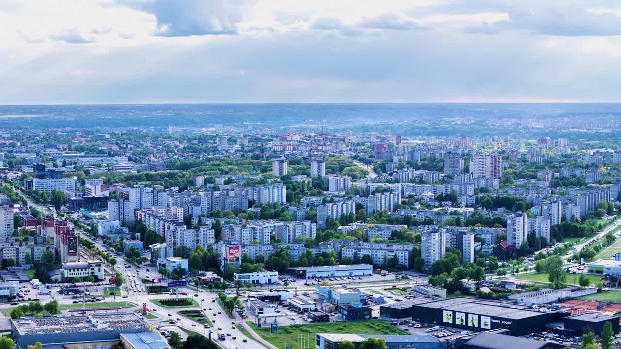 stunning drone shot of Kalnieciai, focusing on the dense pattern of aged apartment blocks amid tree-lined streets