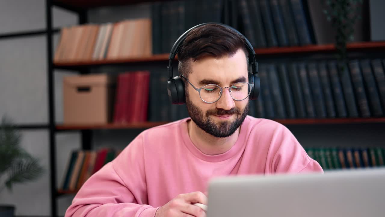 Smart male student listening internet webinar talking online video call notes working library desk
