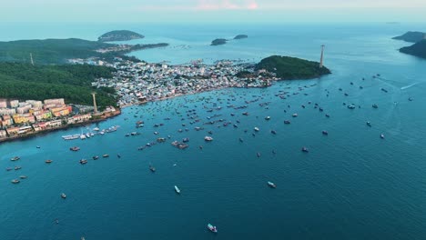 drone shot of phu quoc's fishing village, vietnam. boats dot the sea near shore with a cable car line. captures island life and coastal activity.