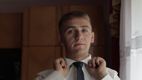 handsome groom fixes his shirt. wedding morning. businessman. slow motion