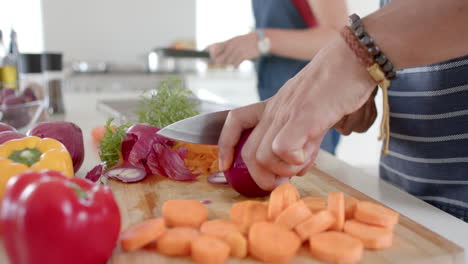 pareja diversa preparando verduras frescas y cortando en la cocina, cámara lenta