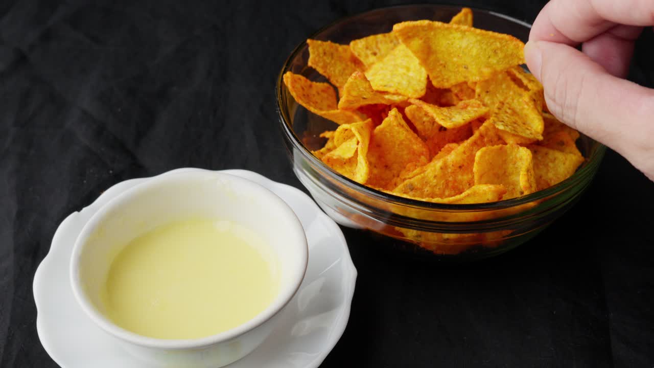 Hand Dipping Crispy Tortilla In Melted Creamy Cheese Sauce In Bowl, Mexican Food