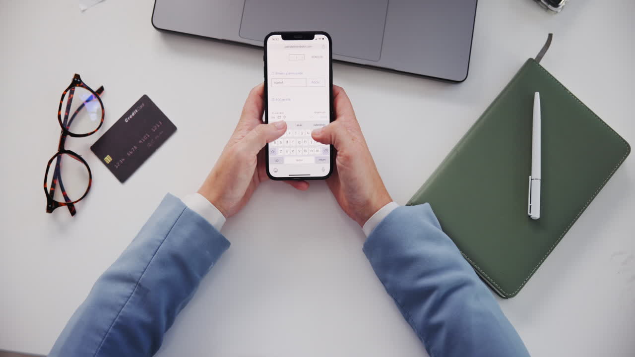 Overhead shot of hands using mobile phone for online payment with credit card and laptop on desk