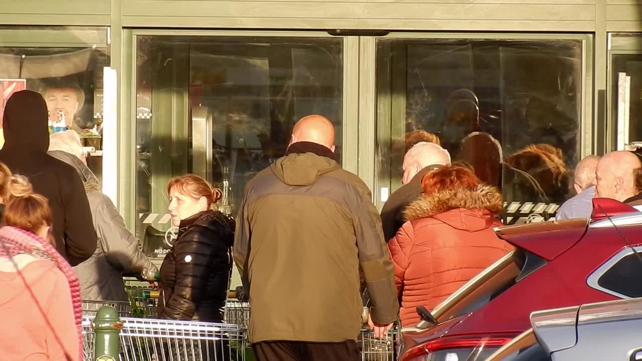 Cornona Covid virus crowd of shoppers panic buying waiting at store doors UK retail