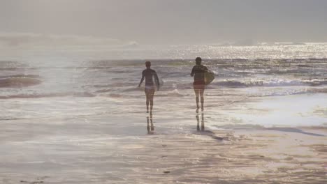 animation of sea over african american couple with surfboards at beach