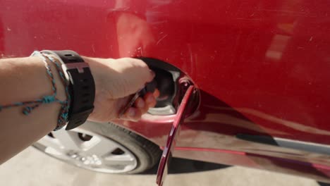 Point-of-view-of-a-person-locking-a-fuel-tank-cap-with-a-key-of-a-red-car