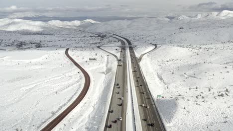 California-highway-through-snow-covered-mountainside,-aerial-view