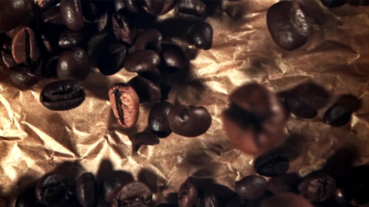 Chicchi di caffè tostati che cadono su carta marrone accartocciata