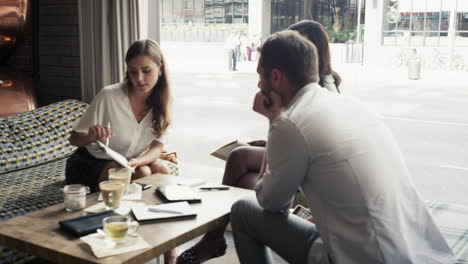 Gente-De-Negocios-Reunida-En-Una-Cafetería-Usando-Una-Tableta-Digital