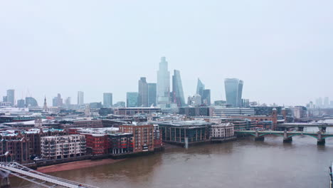 Aumento-De-La-Toma-Aérea-De-Londres-Con-Drones-De-La-Nieve-Que-Cae-Sobre-Los-Rascacielos-De-La-Ciudad-De-Londres-Desde-El-Río-Támesis