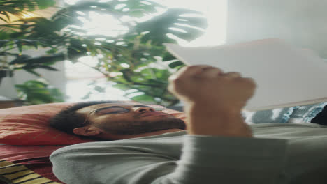 man resting on sofa and reading book
