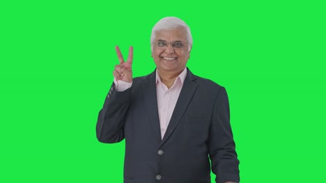 Happy-Indian-senior-manager-showing-victory-sign-Green-screen