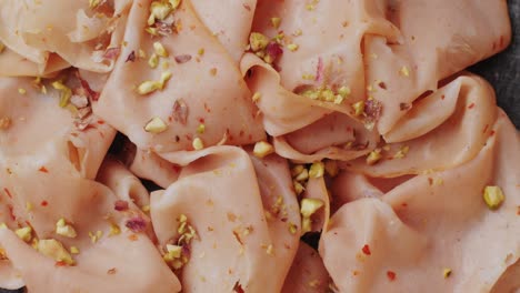 ham italian mordatella, man slices of traditional italian antipasti mortadella sausage on a wooden cutting board, close up macro of chicken or turkey jamon, fat breakfast dish.