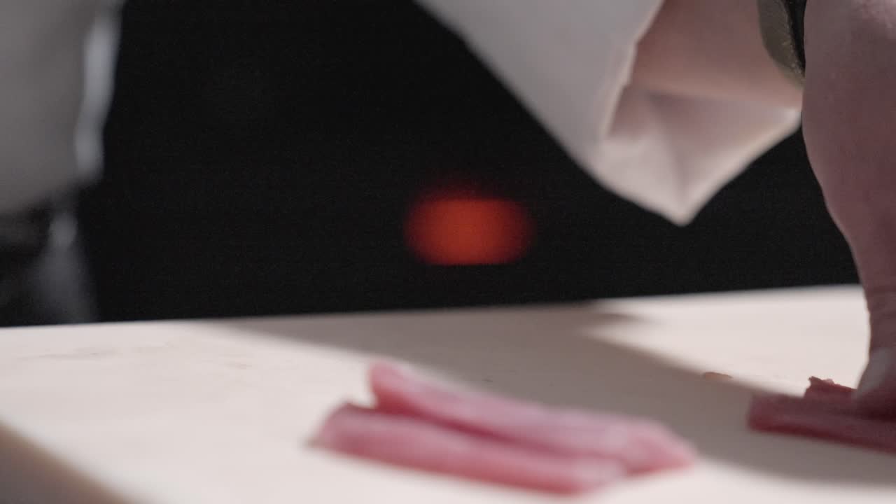 A sushi chef textures fresh tuna slices for sushi, showcasing precise culinary techniques. Perfect for highlighting sushi preparation, Japanese cuisine, and professional food skills in action.