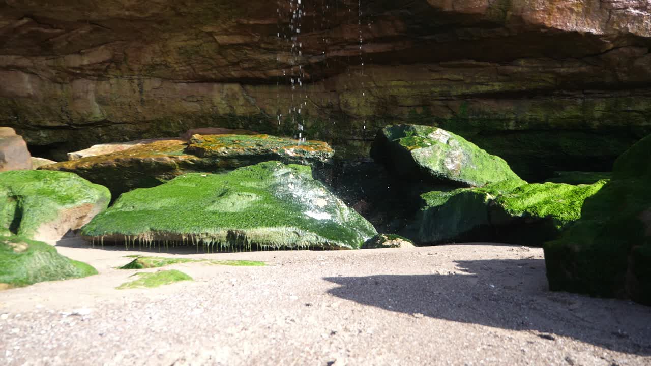 화창한 날 이끼 낀 바위 위에 작은 폭포가 떨어지는 느린 동작