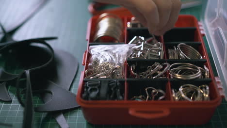 Professional tailor hand takes accessory from red box