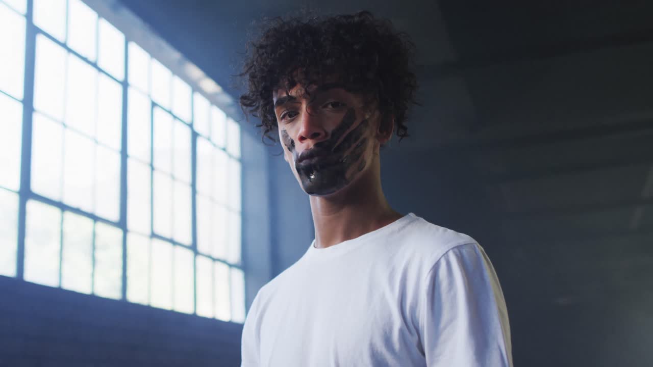 портрет афроамериканца с отметкой руки на рту, стоящего в пустом парковочном гараже